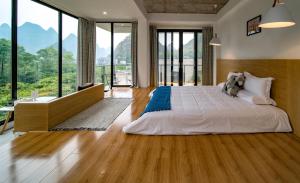 1 dormitorio con 1 cama grande y ventanas grandes en Yangshuo Serene Cove Hotel en Yangshuo