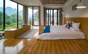 Yangshuo Serene Cove Hotel في يانغتشو: غرفة نوم بسرير كبير ونوافذ كبيرة