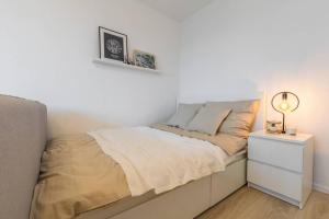 a white bedroom with a bed and a night stand at Sauber und modern, Netflix, Wifi, Leipzig Flair, Küche in Leipzig