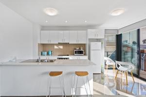 a kitchen with white cabinets and a counter with stools at Soho 203 in Geelong