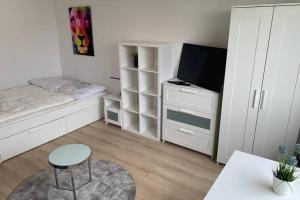 a small white bedroom with a bed and a television at 1 Zi-Whg, Netflix, Wifi, Küche, 15min zum Zentrum in Leipzig