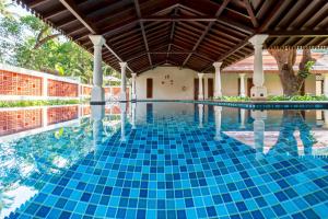 a swimming pool with a blue tile floor and a wooden ceiling at amã Stays & Trails Villa Siolim, Goa in Siolim