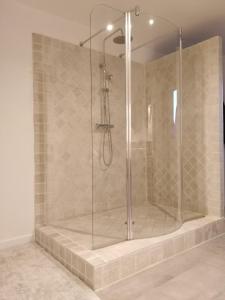 um chuveiro com uma porta de vidro na casa de banho em A deux pas de St Cirq Lapopie, La chambre du "cocher" des Murets de L'isa em Esclauzels