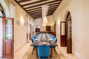 a long dining room with a long table and blue chairs at amã Stays & Trails Villa Siolim, Goa in Siolim