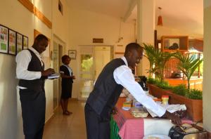 dos hombres parados frente a una mesa con comida en Sunset Hotel Entebbe, en Entebbe