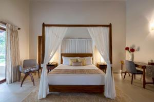 a bedroom with a canopy bed and a desk at amã Stays & Trails Villa Siolim, Goa in Siolim +7 photos