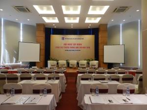 a conference room with tables and chairs and two screens at Danang Petro Hotel in Da Nang