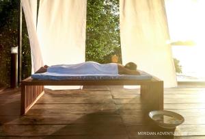 Een man op een bed op een tafel bij Meridian Adventure Marina Club & Resort in Saonek