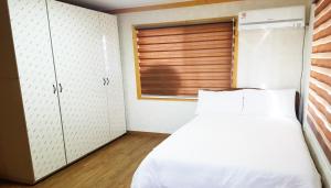 a bedroom with a white bed and a window at Red Windmill Pension in Jeju