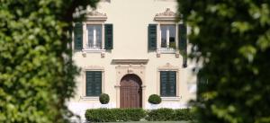 維洛納的住宿－Madonna Villa Baietta，白色的房子,有绿色百叶窗和棕色的门