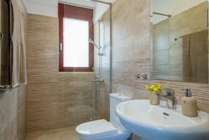 La salle de bains est pourvue d'un lavabo, de toilettes et d'un miroir. dans l'établissement Villa PhenΩmena Apartments, à Kókkinon Khoríon