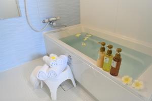 een badkamer met een bad, handdoeken en een wastafel bij Pine Hills Hotel Miyakojima in Miyako Island