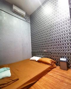 a small room with a bed with a wall at Cilacap Guest House in Cilacap