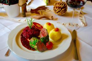 einen Teller mit Essen auf einem Tisch mit einem Glas Wein in der Unterkunft Landgasthof Hirschen Untermettingen in Ühlingen-Birkendorf