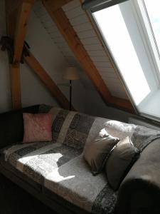 a couch with pillows in a room with a window at Ferienwohnung im Neubauernweg 3 in Hoppegarten