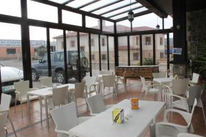 a restaurant with white tables and chairs and a car at Hostal Cabañas in Carboneras de Guadazaón +22 photos