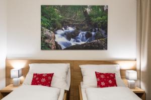 two beds in a room with a waterfall painting on the wall at Hotel Jasná in Belá