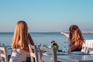 two women sitting at a table looking out at the ocean at Golden Star City Resort in Perea
