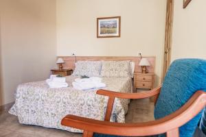 um quarto com uma cama e uma cadeira azul em Apartamentos Maribel em Calaceite