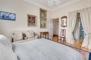 a white bedroom with a bed and a chandelier at Richmond - 2 Bed court flat with allocated parking in Richmond