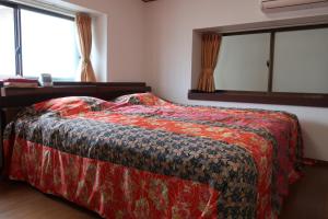 萩ゲストハウスラビット في هاجي: غرفة نوم بسرير وبطانية حمراء ونوافذ