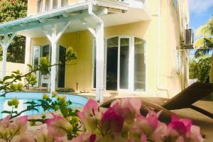 a house with a swimming pool and flowers in front of it at Le Rock @ Calodyne in Grand Gaube