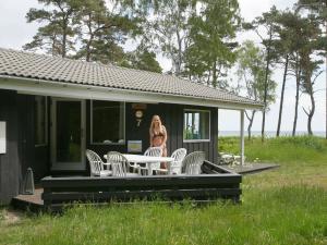 a woman standing on the porch of a house at Cozy Holiday Home in Nexo with Sauna in Snogebæk