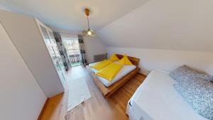 a small room with a bed with yellow pillows at Apartementhaus Schöndorfer in Strobl