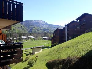 a green hill with buildings and a mountain in the background at OURSONS 1 in Morillon
