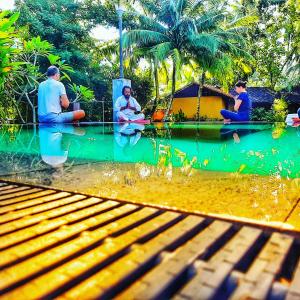 un grupo de personas sentadas frente a un estanque en Villa Velmarie Yoga and Ayurveda house all inclusive, en Beruwala