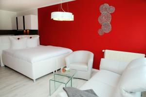 - un salon avec un canapé blanc et un mur rouge dans l'établissement Appartementhaus Sanssouci, à Kühlungsborn