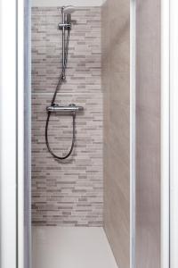 a shower in a bathroom with a brick wall at Appartamenti GG - Big and central in Livigno