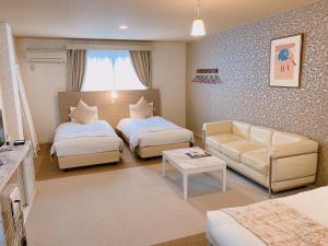 - un salon avec deux lits et un canapé dans l'établissement Sora Hotel Karuizawa Outlet, à Karuizawa