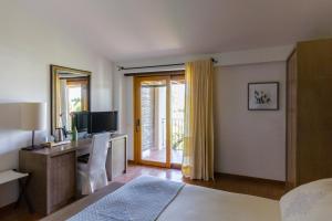 a bedroom with a bed and a tv and a window at Hotel Aquadulci in Chia