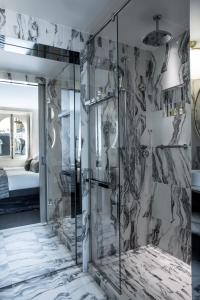 uma casa de banho com um chuveiro e uma porta de vidro em La Clef Champs-Élysées Paris by The Crest Collection em Paris
