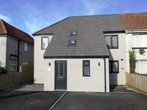 a white house with a black roof at 2 Bedroom Apartments in Filton by Cliftonvalley Apartments in Bristol