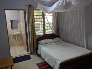 a bedroom with a bed and a bathroom with a window at Kambua Resort in Libwezi