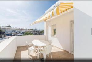 Biały balkon z białym stołem i krzesłami w obiekcie Apartamento Terraza soleada w mieście Conil de la Frontera