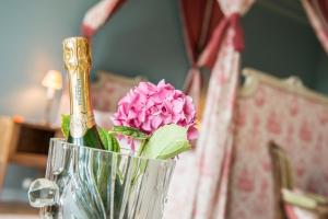 een vaas met een roze bloem erin op een tafel bij Manoir De Ponsay in Chantonnay