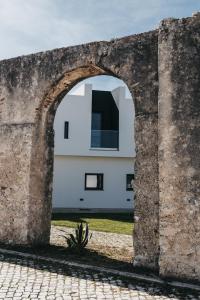an archway in a wall next to a building at &Tales Suites - Óbidos in Óbidos