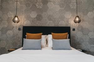 een slaapkamer met een wit bed met 2 kussens bij Obidos Aquae Ductus Suites in Óbidos