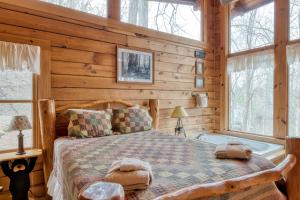 a log cabin bedroom with a bed and a tub at Amazing Grace #25 by Venture Smoky Mountains in Sevierville