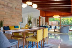 a dining room with a wooden table and yellow chairs at Villa Perfetto Plaza in Palm Springs