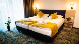 una camera d'albergo con un grande letto con lenzuola gialle di Plaża Resort a Łeba