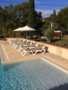 a group of lounge chairs and an umbrella next to a pool at Appart'Hôtel A Punta in Galeria