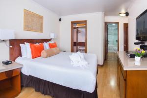 1 dormitorio con 1 cama blanca grande y TV en Lancaster House, en Bogotá