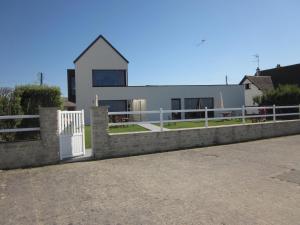 une maison avec une clôture blanche devant elle dans l'établissement Gîtes " Arromanches" ou "Bord de Mer PMR" 2 chambres en FRONT DE MER à Asnelles , 3km d'Arromanches, 10km de Bayeux, à Asnelles