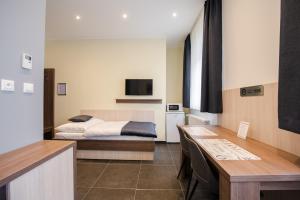 een slaapkamer met een bed en een bureau met een tafel bij Apartments Danube in Bratislava
