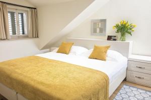 a bedroom with a white bed with a yellow blanket at Palmotta Palace in Dubrovnik