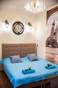 クラクフにあるApartment Centrumのベッドルーム1室(青いシーツと時計付きのベッド1台付)